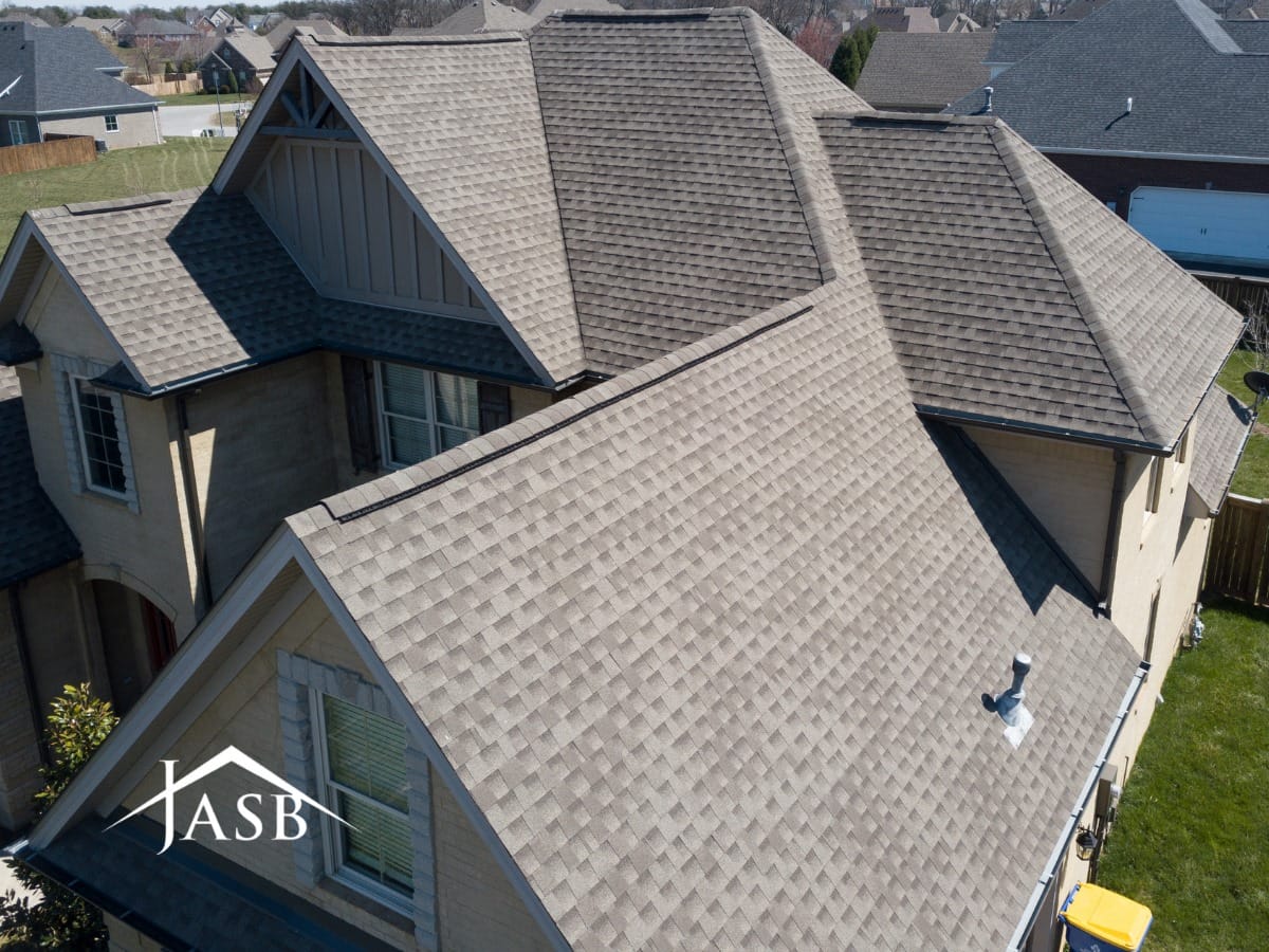 An aerial view of a house with a shingled roof being worked on by a contractor in Austin, TX.