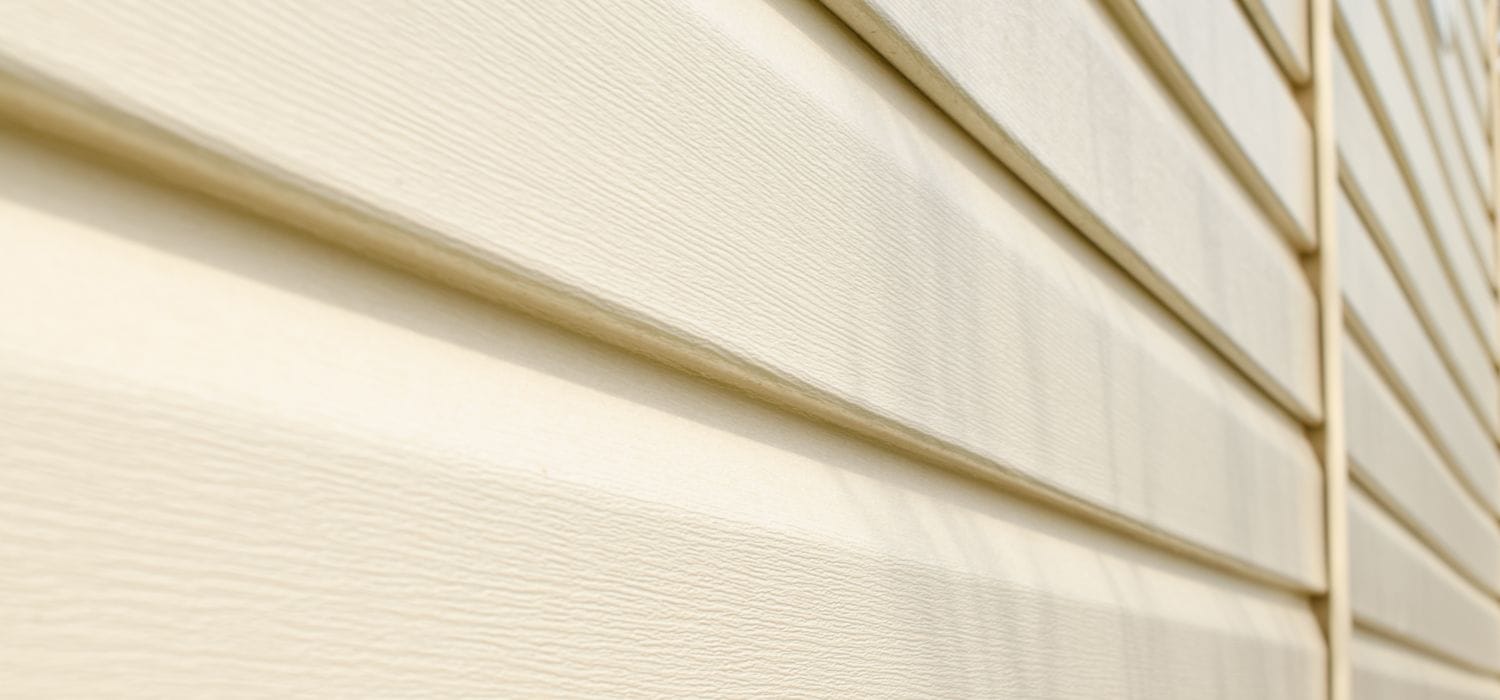 Close-up view of clean beige vinyl siding on a home exterior, showing the smooth texture and well-maintained surface.