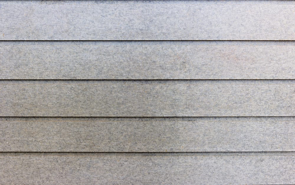 Close-up of horizontal gray fiber cement siding boards on a building exterior, showing a uniform pattern and subtle texture.